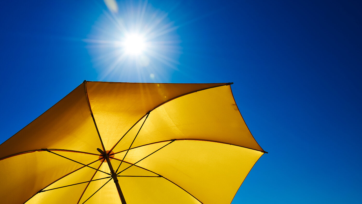 Photograph of a yellow umbrella and the sun